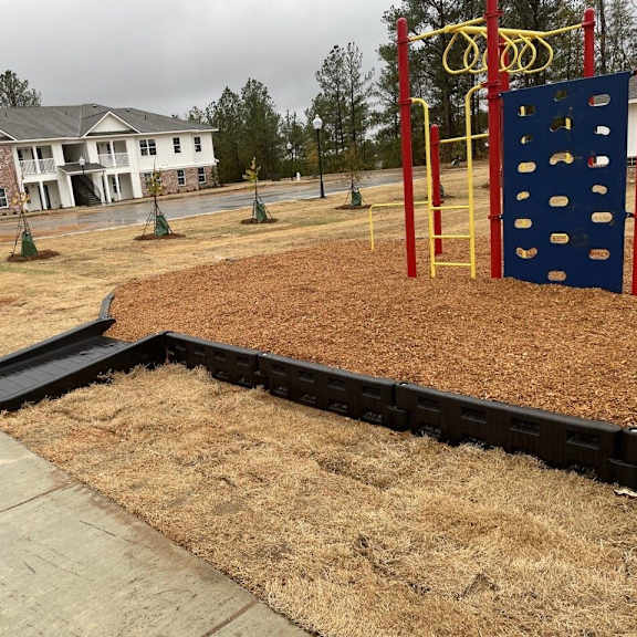 a childrens play area with a wooden deck and a blue and yellow playset
