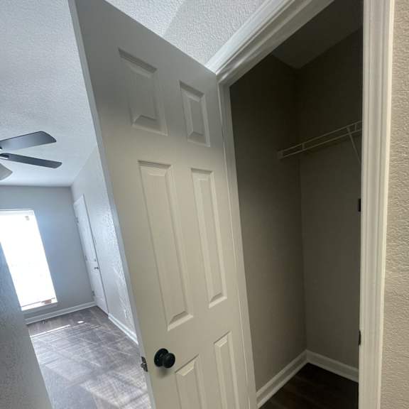 a white door is in a hallway with wood flooring.