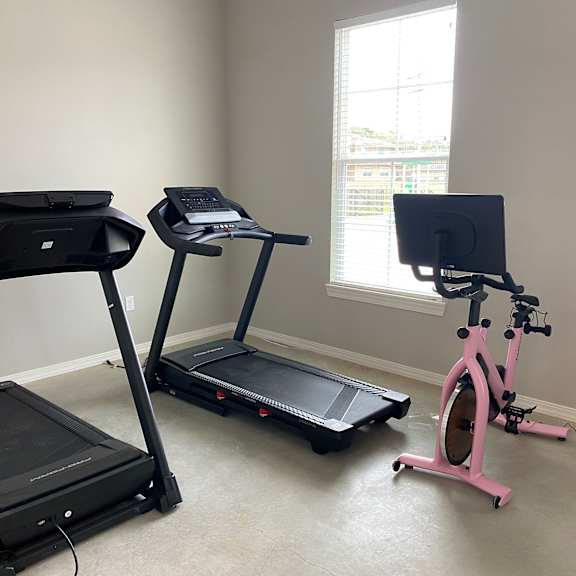 two exercise machines and a bike in a room with a window