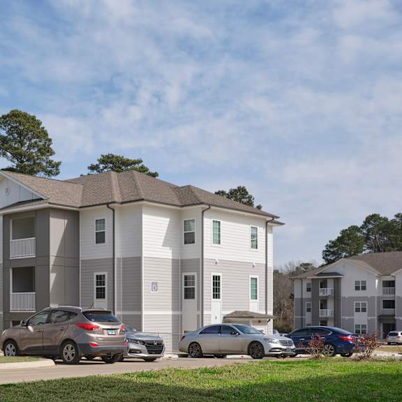 a grey apartment building with cars parked in front.