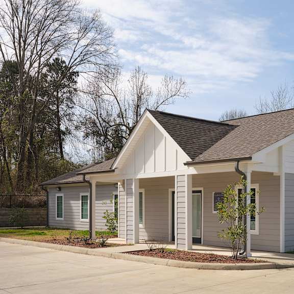 a small white house with a brown roof and a grey front porch.