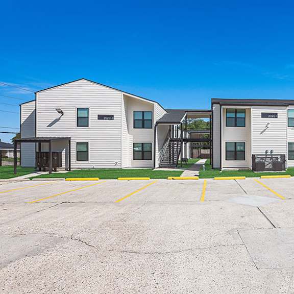 a parking lot in front of a building with a clear blue sky.