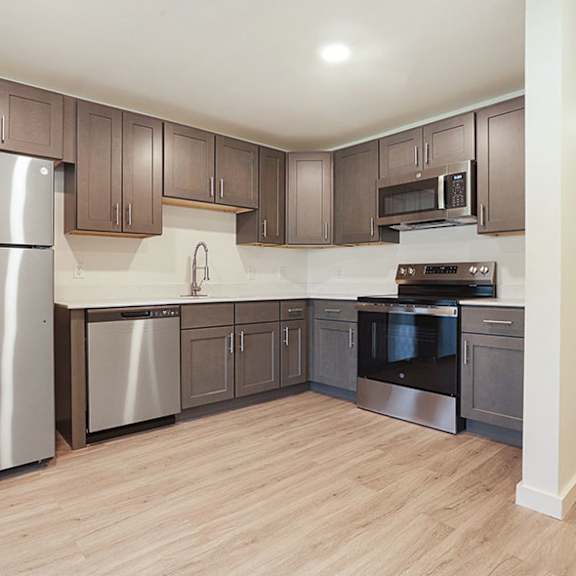 a kitchen with a refrigerator, microwave, oven, and sink.