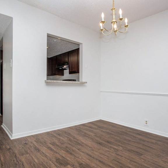 an empty living room with a window and a chandelier