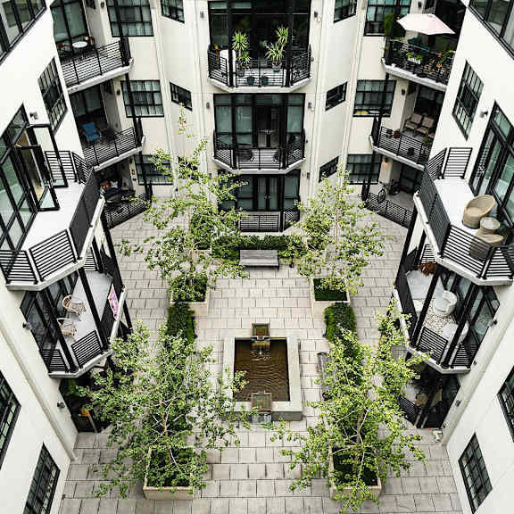 a courtyard surrounded by balconies with plants on the ground.