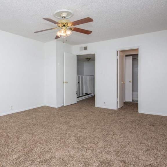 an empty living room with a ceiling fan