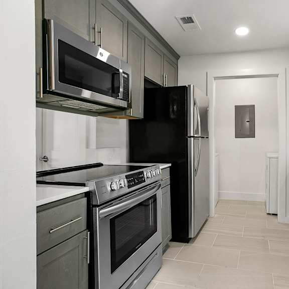 a kitchen with a black refrigerator and stainless steel appliances.
