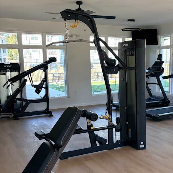 a gym with a variety of equipment including treadmills, elliptical machines, and a stationary bike.