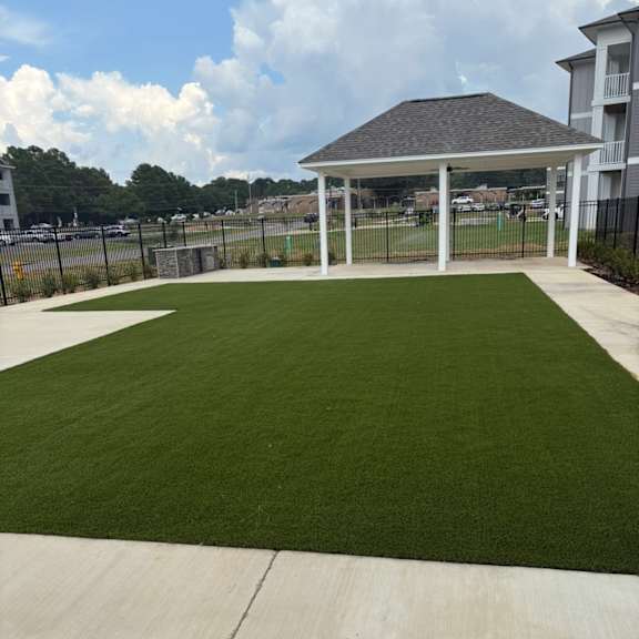 a gazebo is surrounded by a fence and a green lawn.