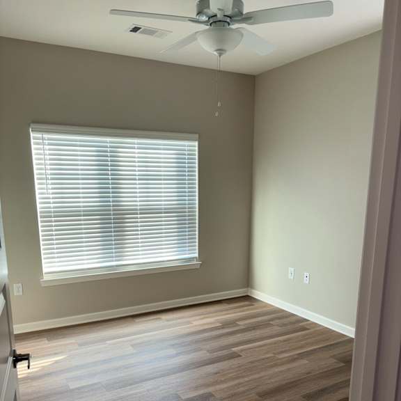 a room with a ceiling fan and a window with blinds.