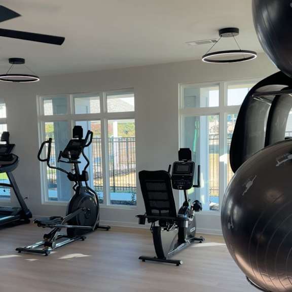 a gym with a treadmill, a stationary bike, a rowing machine, and a weight training area.