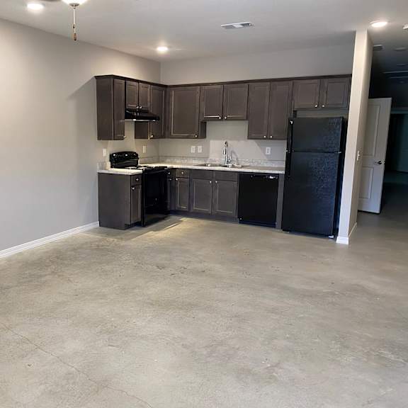 an empty kitchen with black appliances and dark cabinets