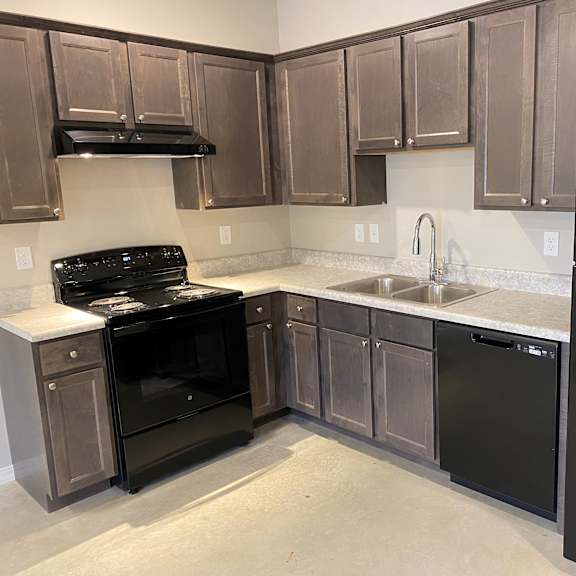 an empty kitchen with black appliances and wooden cabinets