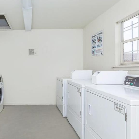 a row of white washing machines in a laundromat.