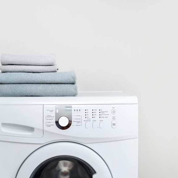 a row of white front load washing machines in a laundromat.