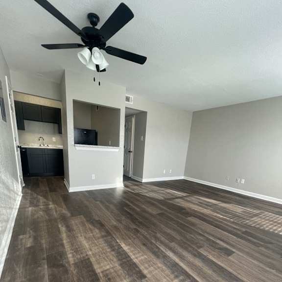 a room with a ceiling fan and wood flooring.
