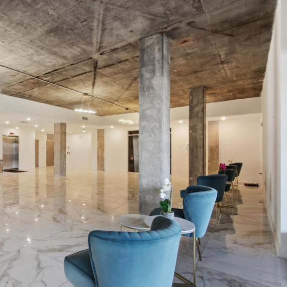 a large room with marble floors and a row of blue chairs.