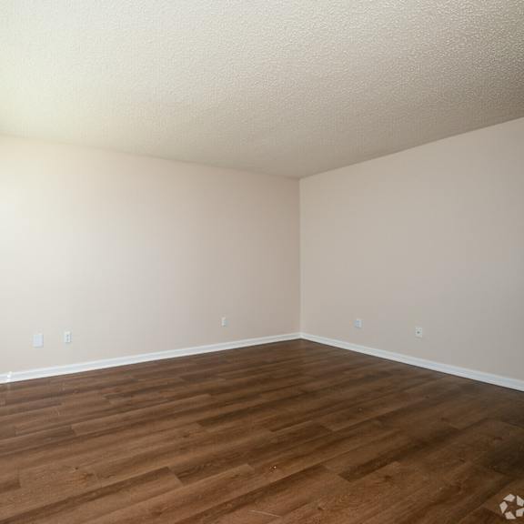 a room with wooden flooring and a window with blinds.