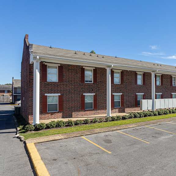 a parking lot in front of a brick building with a car parked.