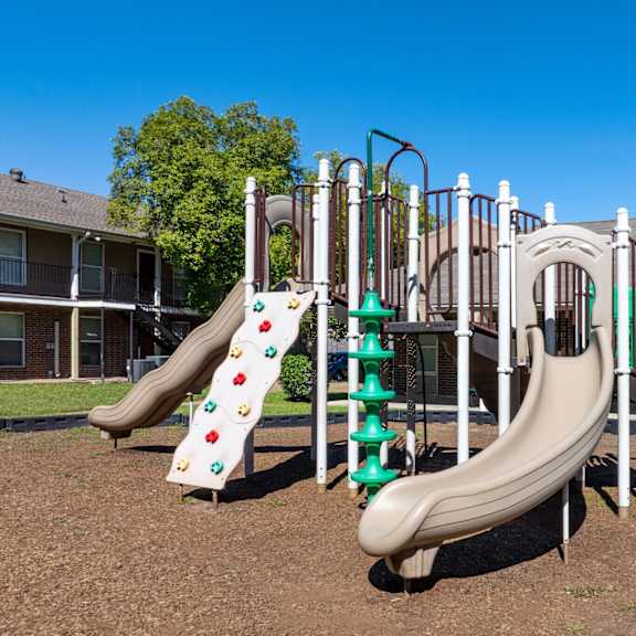 a playground with a green and white slide and a red and white slide.