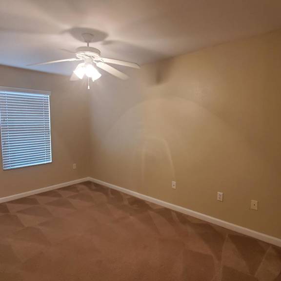 a room with a ceiling fan and a window with blinds.