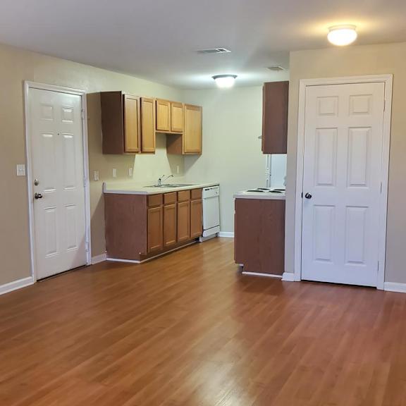 a kitchen with wooden floors and white walls.