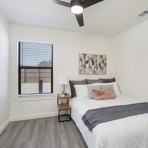 a bedroom with a bed, a ceiling fan, and a window with blinds.