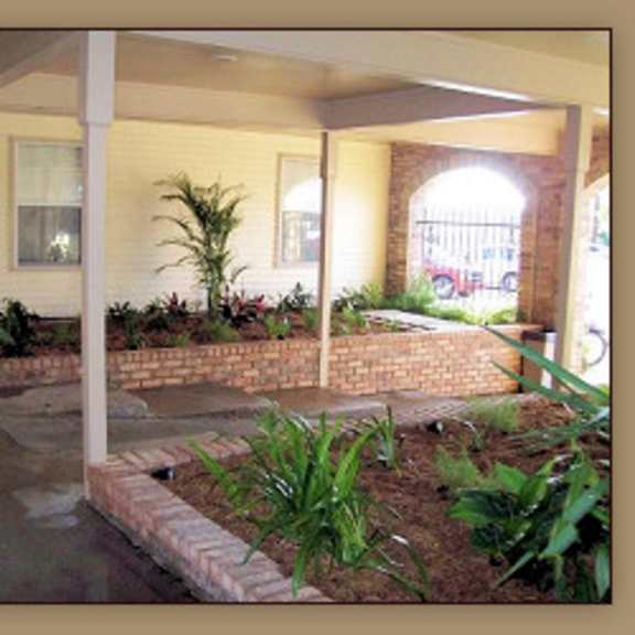 a patio with a brick wall and plants.