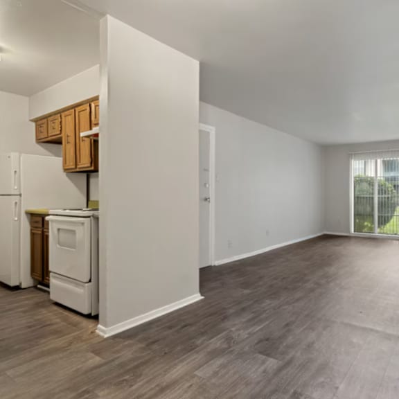 a spacious empty room with wooden flooring and white walls.
