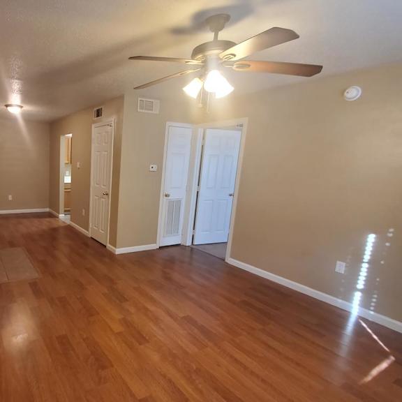 a long hallway with wood floors and a ceiling fan.