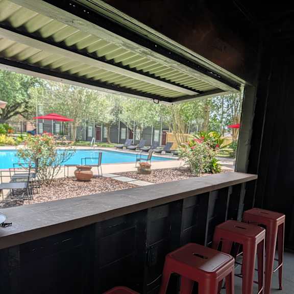 a row of red stools are lined up by a pool.