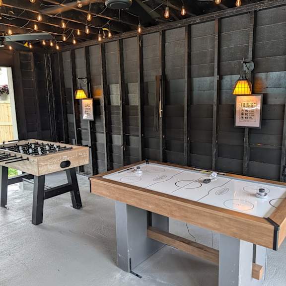 a shuffleboard table is in a room with a dark wood wall and a chess table.