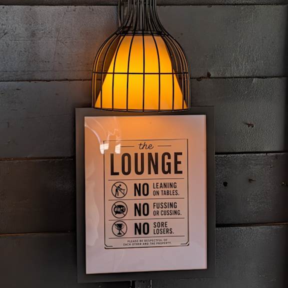 a sign for the lounge with a light hanging above it.