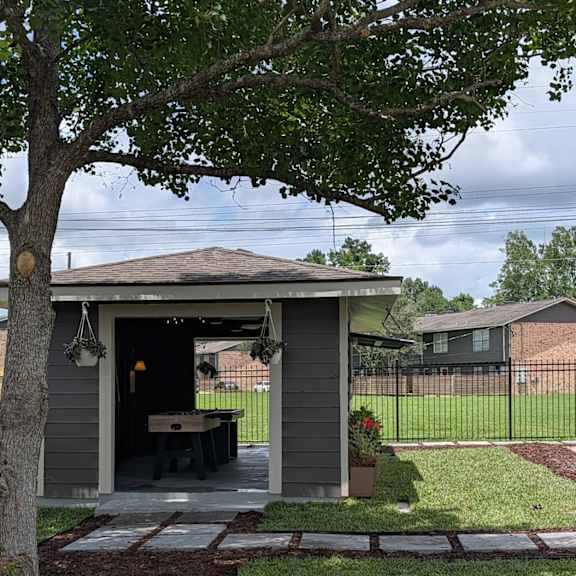 a small building with a porch and a tree in front of it.