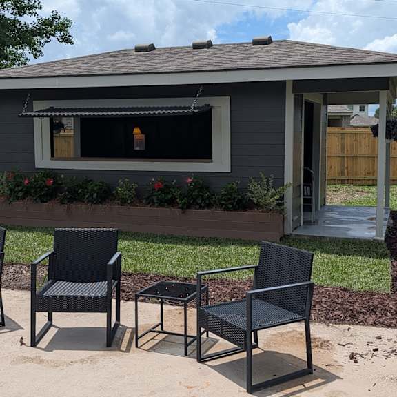 two black chairs and a table are on a patio.