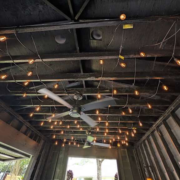 a ceiling fan is hanging from the ceiling with lights strung up around it.