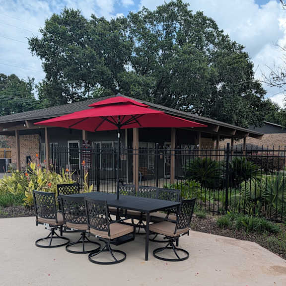 a red umbrella is over a table with chairs.