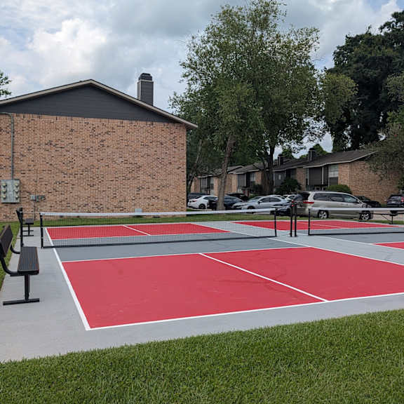 a red and white basketball court in front of a brick building.