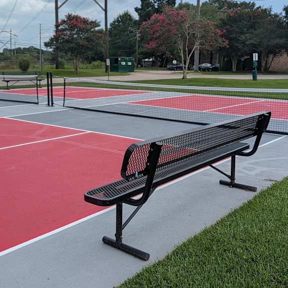 a black bench sits on a red track.