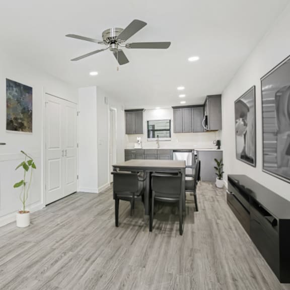 a modern interior with a staircase, a dining table, and a ceiling fan.
