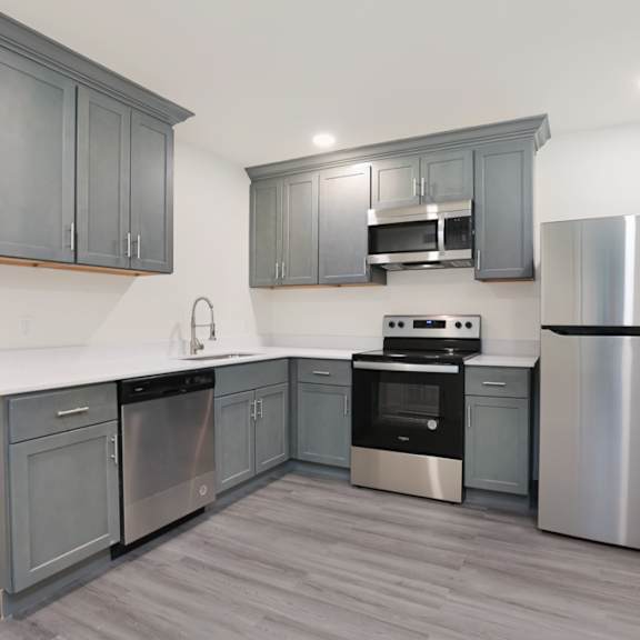 a modern kitchen with stainless steel appliances and grey cabinets.