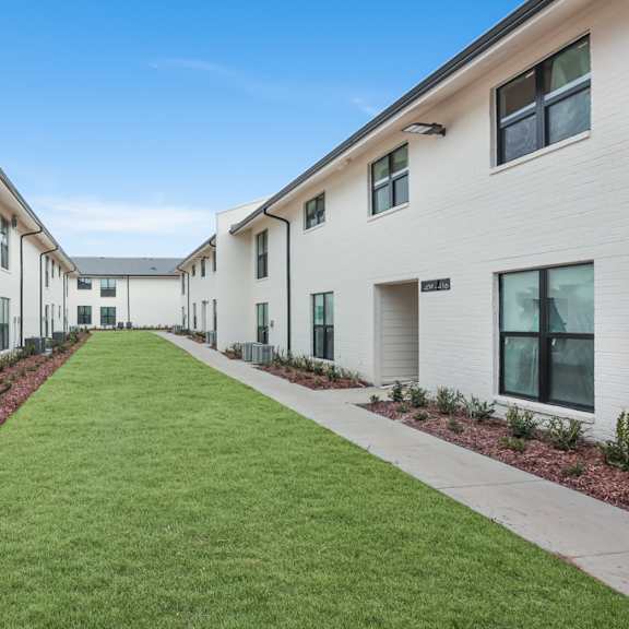 a long white building with a green lawn in front.