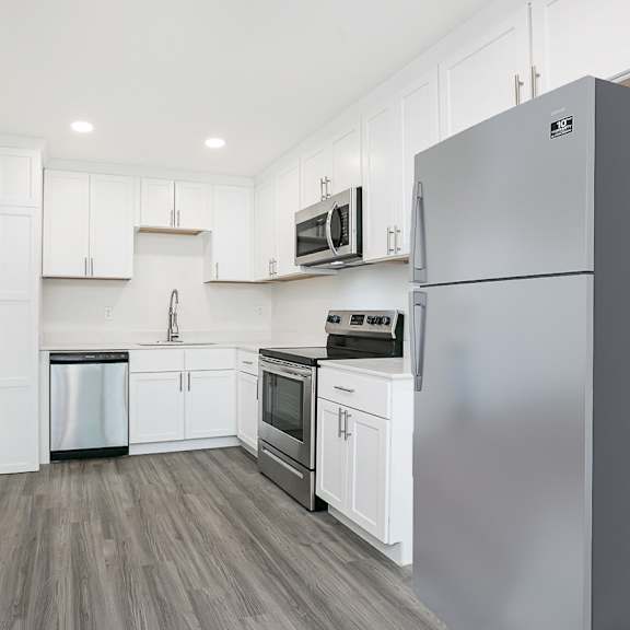 a kitchen with white cabinets and a grey refrigerator.