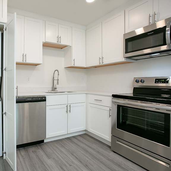 a kitchen with white cabinets and stainless steel appliances.