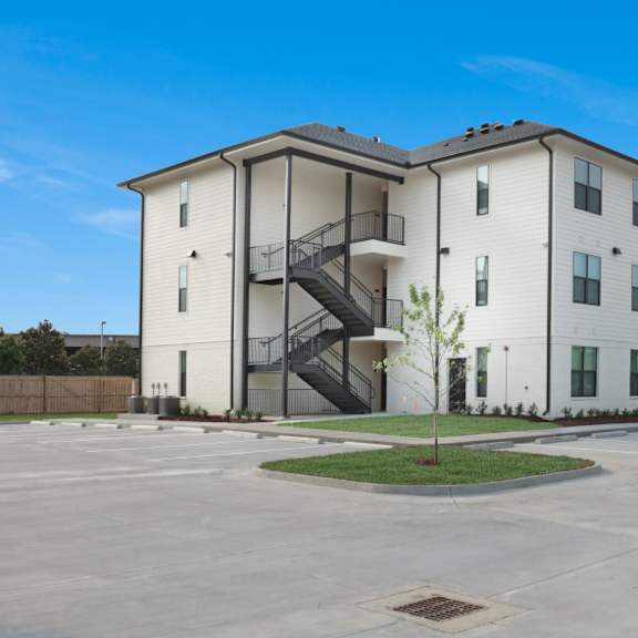 a white apartment building with a black and white staircase.