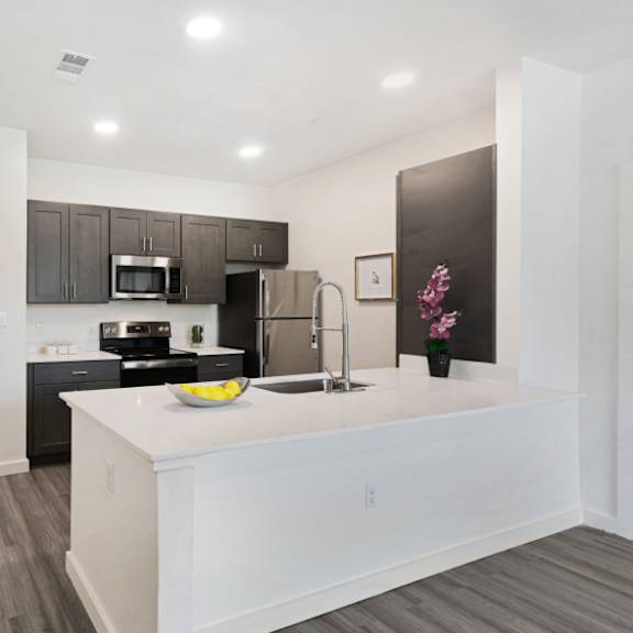 a kitchen with a white island and dark wood floors.