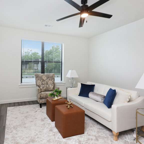 a living room with a white couch, a green coffee table, and a ceiling fan.