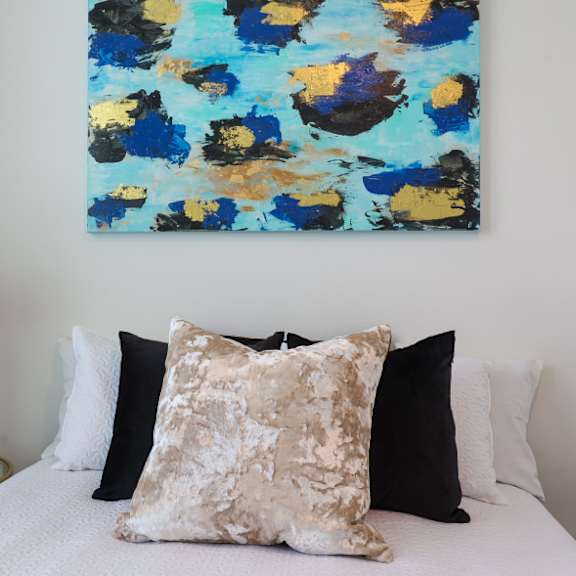 a bed with a white comforter and a painting above it.