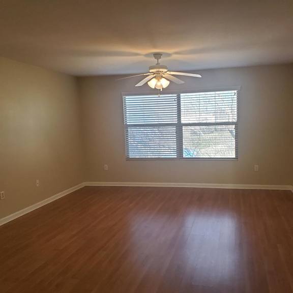 a room with a ceiling fan and a window with blinds.
