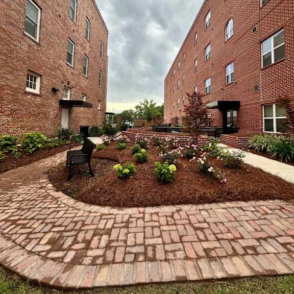 a courtyard with a bench and a brick building